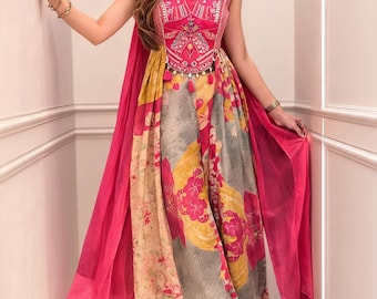 May include: A sleeveless dress featuring a vibrant pink bodice with intricate embroidery and a high neck collar. The skirt displays a multi-colored floral pattern in shades of yellow, grey, and pink, complemented by a flowing pink cape-like overlay.