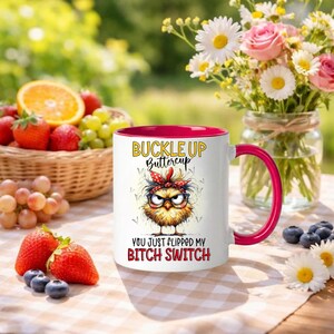 May include: White ceramic mug with a red interior and handle. The mug features a cartoon chick with glasses and a red bandana, and the text "BUCKLE UP Buttercup" and "YOU JUST FLIPPED MY BITCH SWITCH".