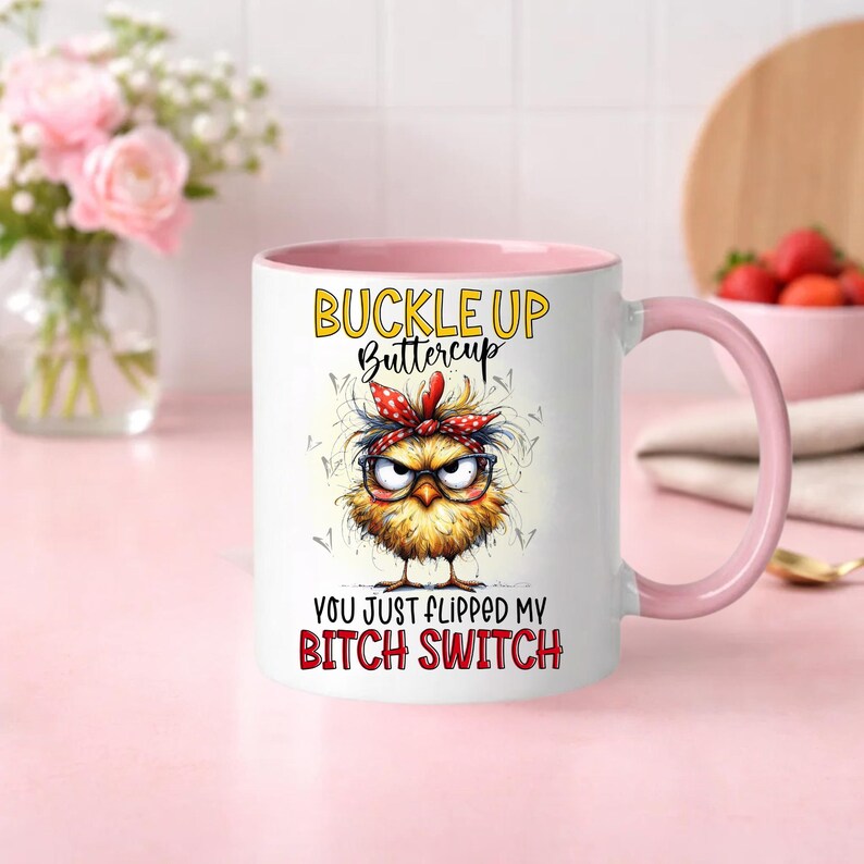 May include: White ceramic mug with a pink interior and handle. The mug features a cartoon chick with glasses and a red bandana, and the text "BUCKLE UP Buttercup" and "YOU JUST FLIPPED MY BITCH SWITCH".