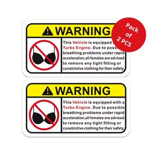 以下が含まれることがあります： 黄と黒の縁取りのある2つの警告ステッカー。ステッカーには警告記号と「この車両にはターボエンジンが搭載されています。呼吸困難の可能性があるため...」と書かれたテキストがあります。赤い円には「2個入り」と書かれています。