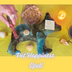 May include: A dark blue and green glittery dog-shaped figurine with a small white paper note attached that reads YOUR NAME + DATE OF BIRTH. The figurine is surrounded by crystals, a small heart-shaped stone, and a lit candle. Text reads Pet Happiness Spell.