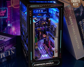 May include: A miniature DIY Cyberworld diorama kit with LED lights, depicting a detailed street scene with buildings, signs, and a curved road. The kit includes the text "Cyberworldworld" and "DIY Crafts Kits". The diorama is displayed next to books.
