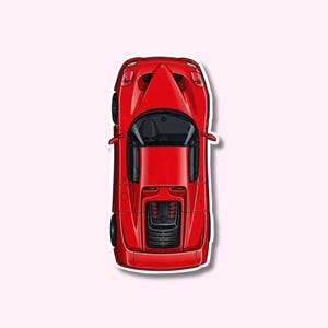 May include: A red sports car sticker, viewed from above, with a glossy finish. The car features a sleek design with black wheels and a detailed engine compartment. The sticker has a white border and is set against a light pink background.