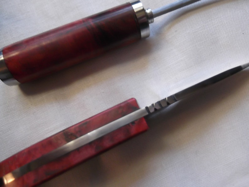 May include: A red and silver pocket knife with a wooden handle. The blade is partially open and the handle has a wood grain pattern.