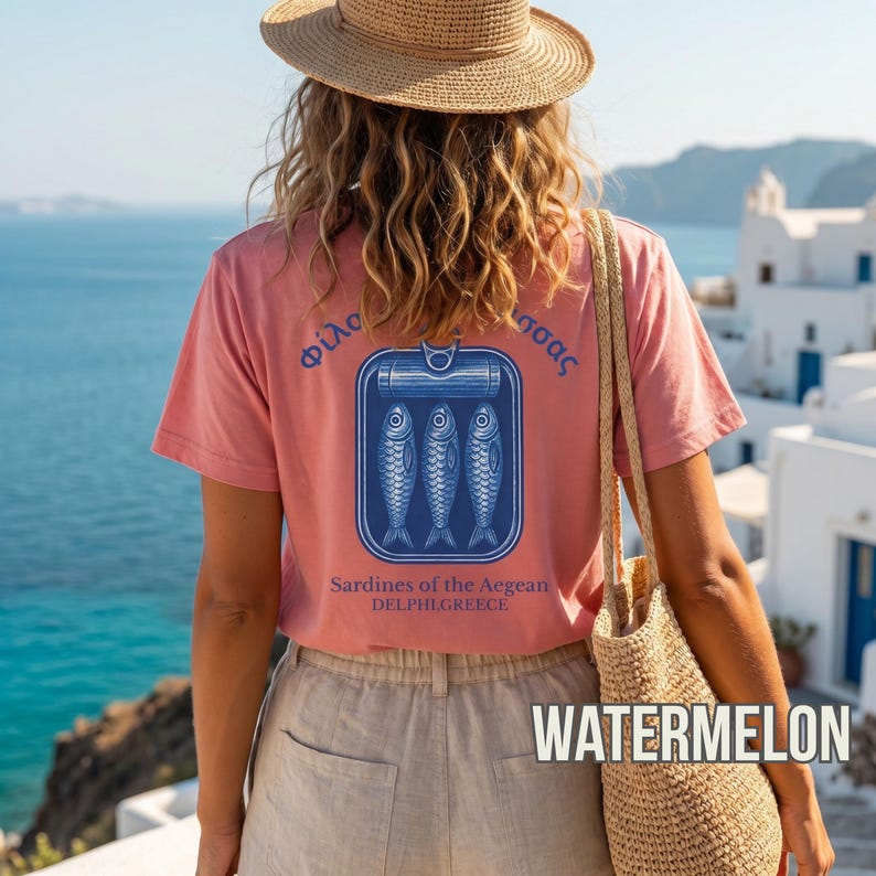 Tinned fish coastal tee inspired by old world seafood labels and Mediterranean beach culture. The graphic back print displays three sardines inside a retro tin can with Greek lettering and “Sardines of the Aegean” typography in vintage blue ink. Printed on a Comfort Colors 1717 garment dyed shirt for a relaxed, premium feel ideal for summer fashion, foodie streetwear, and coastal lifestyle outfits.