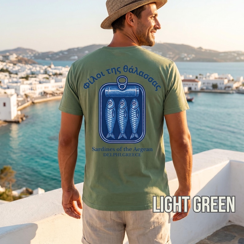 Tinned fish aesthetic shirt designed with a vintage sardine can illustration and Greek inspired coastal typography on the back. This Mediterranean graphic tee combines retro seafood branding with relaxed beach lifestyle fashion, creating a standout Comfort Colors 1717 shirt for summer outfits, coastal vacations, Greek travel lovers, seafood enthusiasts, and anyone seeking unique vintage inspired graphic apparel with a nautical vibe.