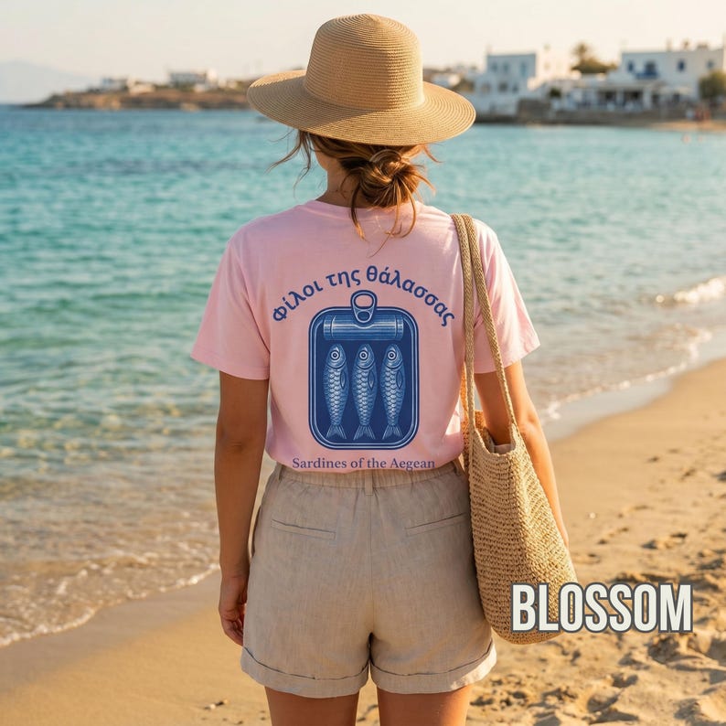 Blossom Comfort Colors 1717 sardine shirt featuring a Mediterranean inspired back print with three illustrated sardines inside a retro fish can design. The Greek typography and vintage coastal artwork create a timeless European summer aesthetic perfect for seaside vacations, beach inspired fashion, foodie gifts, and nautical streetwear collections. Ideal for fans of tinned fish culture, retro graphic tees, and coastal lifestyle clothing.
