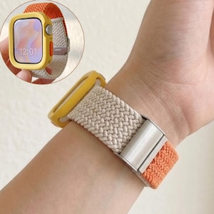May include: A yellow watch case and a beige and orange braided watch strap are shown on a wrist. The watch face displays the time 12:01. The strap has a silver clasp. The watch case and strap are made of a woven material.