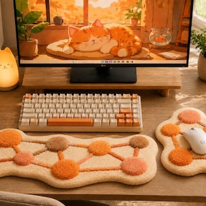 May include: A mechanical keyboard with cream and orange keycaps, a long rectangular tufted wrist rest, and a matching square tufted mouse pad. Both pads feature a cream base with a geometric pattern of interconnected orange and brown circles.