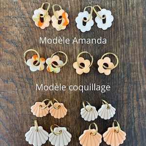 Peut inclure: Une collection de boucles d'oreilles créoles avec des breloques en pâte polymère de formes et couleurs variées. L'ensemble comprend des fleurs nommées Modèle Ambre et Modèle Amanda, et des coquillages nommés Modèle coquillage, avec des anneaux dorés.