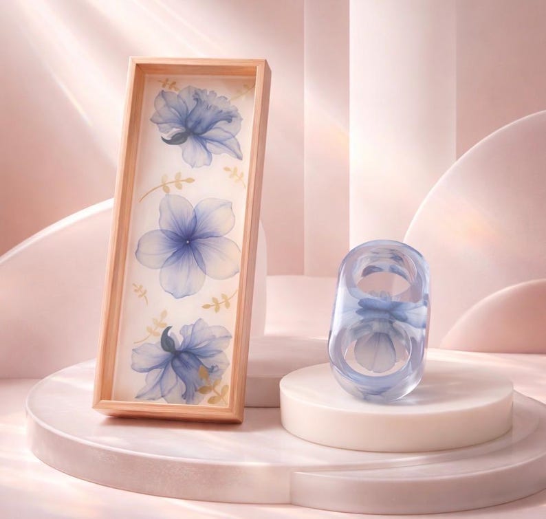 May include: A rectangular wooden tray featuring a white base with three translucent blue floral illustrations and small gold leaf accents, accompanied by a matching translucent blue ring with a floral design inside the clear resin band.
