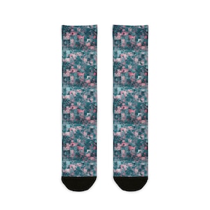 May include: A pair of socks with a repeating pattern of teal, pink, and white squares. The design has a mosaic-like appearance, with abstract shapes and dots. The socks have black toes and heels.