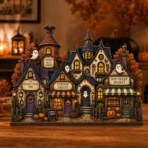 May include: A miniature Halloween village display featuring The Wicked Wren Inn, Pumpkin Bakery, Crow's Rest Tower, and Boo Berry Market. The structure includes illuminated windows, small ghost figures, autumn foliage, and pumpkins on a stone path.
