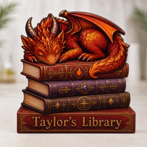 May include: A decorative figurine featuring a sleeping orange and red dragon resting atop a stack of four books. The bottom book is red with the text Taylor's Library printed in gold. The other books are purple, brown, and red with gold details.