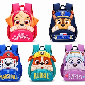 Może przedstawiać: Pięć plecaków z postaciami z Psiego Patrolu. W górnym rzędzie znajduje się różowy plecak Skye i granatowy plecak Chase. W dolnym rzędzie znajduje się niebieski plecak Marshall, turkusowy plecak Rubble i fioletowy plecak Everest. Każdy plecak ma przednią kieszeń z nadrukowanym imieniem postaci oraz boczne kieszenie z siatki.