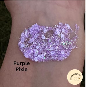 Op de afbeelding: Een staal van paarse glittergel met iriserende zeshoekige en fijne deeltjes. De tekst Purple Pixie is in het zwart gedrukt en een rond logo met de tekst honey stitch co en een bijenpictogram is in de hoek zichtbaar.