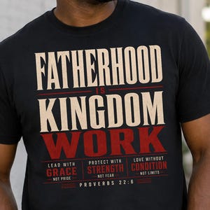 May include: A black short-sleeve t-shirt featuring the text FATHERHOOD IS KINGDOM WORK in cream and red. Below this, the text reads LEAD WITH GRACE NOT PRIDE, PROTECT WITH STRENGTH NOT FEAR, LOVE WITHOUT CONDITION NOT LIMITS, and PROVERBS 22:6.