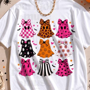 May include: A white short-sleeve t-shirt featuring a graphic print of nine ghosts arranged in a grid. Each ghost wears a large bow and displays a unique pattern, including checkerboard, leopard print, stars, smiley faces, flowers, lightning bolts, and hearts.