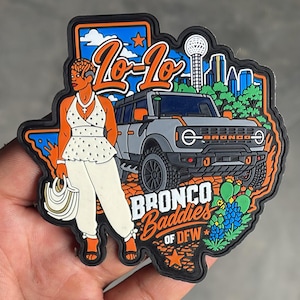 May include: A rubber patch shaped like Texas featuring a gray SUV, a person in a white polka-dot top and pants holding a white bag, and the text Lo-Lo, BRONCO Baddies OF DFW. The design includes a city skyline, blue sky, orange stars, and green cacti.