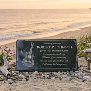 May include: A rectangular black stone memorial plaque featuring an engraved acoustic guitar and the text: In Loving Memory Of ROBERT P. JOHNSON July 18, 1958 - December 16, 2018, Everyday in some small way, Memories of you come our way, Though absent, you are always near, Still missed, loved, always dear.