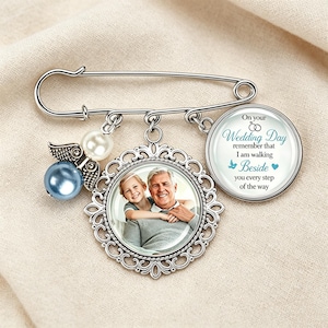May include: A silver-toned safety pin brooch featuring a dangling charm with a photograph of a child and an older man, a round charm with the text On your Wedding Day remember that I am walking Beside you every step of the way, and a pearl bead.