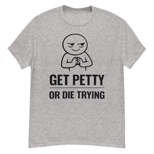 May include: A heather gray t-shirt with a black graphic of a smug-looking stick figure with clasped hands. Below the figure, the text reads "GET PETTY OR DIE TRYING" in a bold, sans-serif font. The shirt is a casual wear item.
