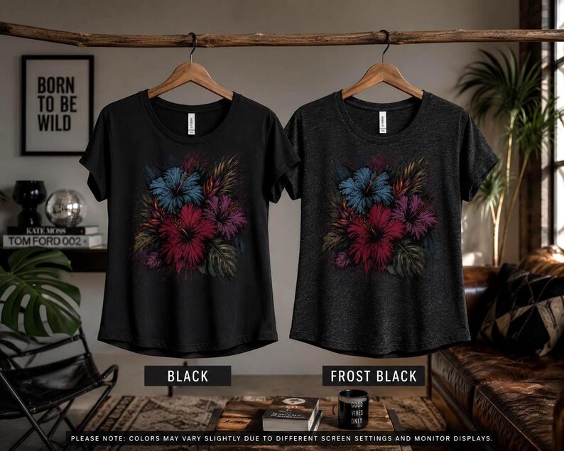 Puede incluir: Dos camisetas, una negra y otra negra helada, cada una con un dise&ntilde;o floral con flores rojas, azules y moradas. Las camisetas cuelgan de perchas de madera. El fondo incluye el texto "BORN TO BE WILD".