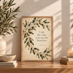 Könnte beinhalten: Ein rechteckiger Wandkunstdruck in einem Holzrahmen mit einer Aquarellillustration eines Olivenzweigkranzes. Der Text lautet, I am the vine; you are the branches. John 15:5, zentriert auf einem cremefarbenen Hintergrund mit grünen Blättern.