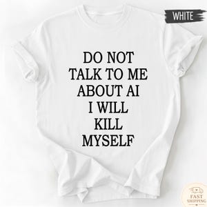 May include: A white short-sleeved t-shirt featuring black text centred on the chest that reads: DO NOT TALK TO ME ABOUT AI I WILL KILL MYSELF. The garment has a crew neckline and a standard fit, with a small label in the corner indicating the colour white.