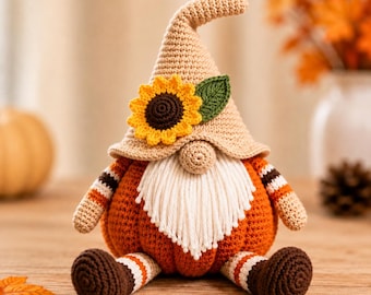 May include: A crochet gnome figurine featuring a tan pointed hat adorned with a yellow sunflower and a green leaf. The gnome has a white yarn beard, a round nose, and a body shaped like an orange pumpkin. It wears striped sleeves and brown feet.