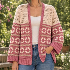 Puede incluir: Un cárdigan de ganchillo con un diseño de bloques de color, con secciones superiores en color crema y una parte inferior compuesta por motivos florales de cuadrados de la abuela en rosa y crema. La prenda tiene mangas largas y frente abierto.