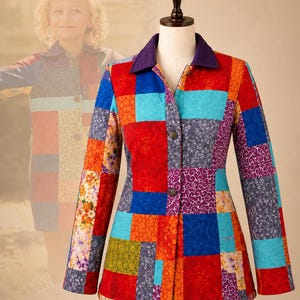 May include: A long-sleeved jacket featuring a vibrant patchwork design with various floral and geometric patterns in shades of red, blue, orange, and purple. The jacket has a solid dark purple collar and a front button closure on a mannequin.