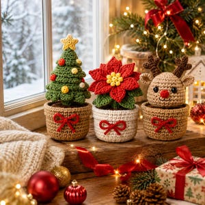 Puede incluir: Tres decoraciones navideñas de ganchillo en macetas: un árbol verde con una estrella amarilla y adornos, una flor de pascua roja y un reno beige con astas marrones y nariz roja. Cada maceta tiene un pequeño lazo rojo de ganchillo.