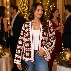 May include: A long-sleeved crochet cardigan featuring a repeating granny square pattern in white, dark green, and deep red. The garment has an open front design, a straight hem, and a white border trim, worn over a plain white top and blue jeans.