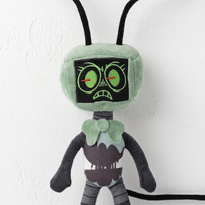 May include: A plush toy robot with a green head and black antennae. The robot's face is a black screen with embroidered green eyes and a frowning mouth. The body is gray and black with a green collar.