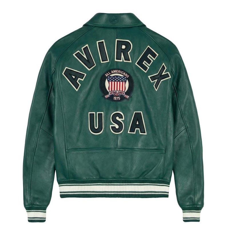 May include: A green leather jacket with the word "AVIREX" arched across the shoulders and "USA" below a circular patch. The patch features a US flag design and the words "ALL AMERICANS" and "ESTABLISHED 1975". The jacket has a white and green striped hem.
