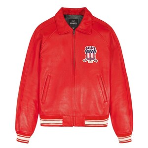 Peut inclure: Veste en cuir rouge vif de style bomber. Col chemise, fermeture &eacute;clair et poignets et ourlet c&ocirc;tel&eacute;s &agrave; rayures blanches. Un &eacute;cusson brod&eacute; avec un motif de drapeau am&eacute;ricain est cousu sur la poitrine.