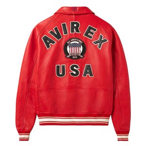 Peut inclure: Veste en cuir rouge vif avec le mot "AVIREX" en lettres blanches sur les &eacute;paules. Le mot "USA" est affich&eacute; en dessous. Un &eacute;cusson circulaire affiche "ALL AMERICANS" et "1975". La veste a des poignets et un ourlet ray&eacute;s blancs et noirs.