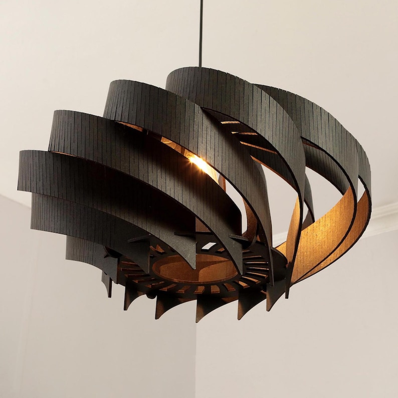 May include: A contemporary pendant light made of dark brown wood. The light features a spiral design with curved, layered wooden slats. The interior has a warm, golden hue, and it hangs from a black cord.
