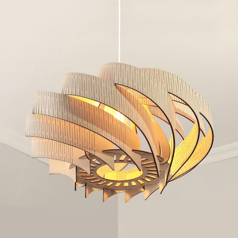 May include: A contemporary wooden pendant light. The light features a layered, spiral design with a natural wood finish and dark detailing. It hangs from a white ceiling, highlighting its unique, artistic form. The light is approximately 60 cm in diameter.