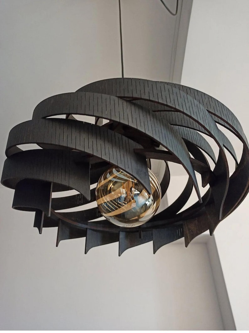 May include: A contemporary pendant light in dark brown. The light fitting has a layered, curved design with a spherical, striped glass bulb. It hangs from a thin black cord, ideal for a living or dining room.