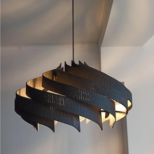May include: A contemporary pendant light in a dark hue. The light features a spiral design with layered, curved panels. The panels have vertical cutouts, and the light source is visible inside. It is suspended from a single black cord.