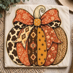 Puede incluir: Una camiseta de color crema con un gran gráfico de una calabaza. La calabaza está compuesta por paneles verticales con varios patrones, incluyendo manchas de vaca, estampados florales, formas geométricas, estrellas y texturas de espiga.