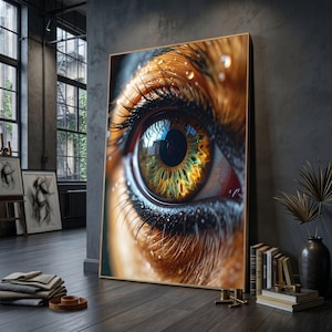 Puede incluir: Una impresión artística enmarcada que presenta un primer plano de un ojo humano. El iris tiene detalles en tonos verdes, amarillos y marrones. Largas pestañas oscuras enmarcan el ojo, y se ven gotas de agua. La obra de arte se exhibe en una habitación con luz natural.