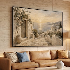 Puede incluir: Una impresión de arte mural rectangular enmarcada que representa una escena costera mediterránea al atardecer. La pintura muestra un edificio de piedra con una enredadera en flor en una maceta grande, un camino empedrado y un mar tranquilo.