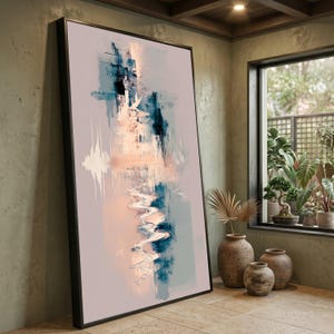 Op de afbeelding: Een groot rechthoekig ingelijst kunstwerk aan de muur met een abstracte compositie met verticale penseelstreken in tinten diep marineblauw, zacht perzik en gedempt crème tegen een licht mauve achtergrond, geplaatst in een zwarte lijst.
