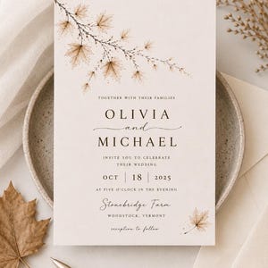 Może przedstawiać: Prostokątne zaproszenie ślubne na kremowym tle z brązowymi akwarelowymi ilustracjami liści klonu. Tekst brzmi: TOGETHER WITH THEIR FAMILIES, OLIVIA and MICHAEL, INVITE YOU TO CELEBRATE THEIR WEDDING, OCT 18 2025, AT FIVE O'CLOCK IN THE EVENING, Stonebridge Farm, WOODSTOCK, VERMONT, reception to follow.