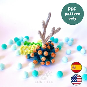 Puede incluir: Una estructura de arrecife de coral tejida a ganchillo con una pieza central beige ramificada, rodeada de corales tubulares de color verde azulado oscuro y naranja y zarcillos en espiral verde claro, con pompones azul claro y verde azulado. Texto: PDF pattern only.