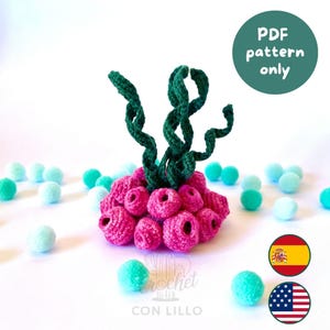May include: A handmade crochet coral reef with green seaweed-like structures and pink coral formations. The image includes small, light blue and green pom-poms scattered around the reef. The text "PDF pattern only" is visible.