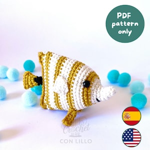 Puede incluir: Un juguete de pez tejido a ganchillo con rayas horizontales alternas en hilo amarillo mostaza y blanco. El pez tiene un ojo de cuenta negra, una pequeña aleta blanca y una cola amarilla con un acento negro. Una insignia circular dice PDF pattern only.